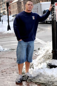 a man in shorts standing next to a pole in the snow