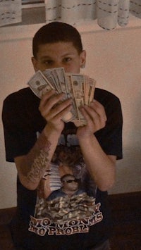 a young man holding up a stack of money