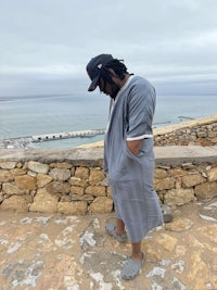 a man standing on a stone wall next to the ocean