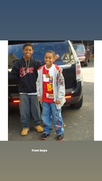 two boys standing in front of a car